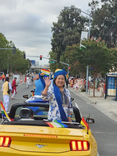 Liang Chao greeting community members from a parade car